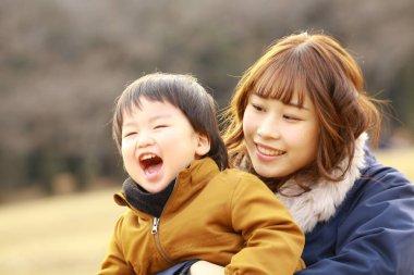 Genç Asyalı anne oğluyla parkta eğleniyor.  