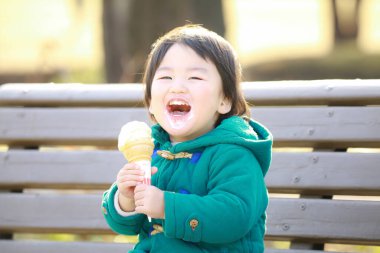Parkta dondurma yiyen küçük çocuk.
