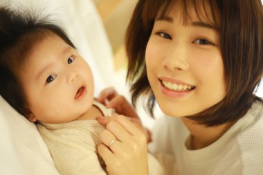 Genç Asyalı anne evde küçük bebekle eğleniyor. 