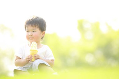 Parkta dondurma yiyen sevimli küçük çocuk.