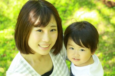 Genç Asyalı anne oğluyla parkta eğleniyor.  