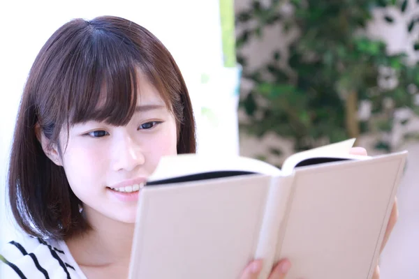 美丽的年轻亚洲女人在家里看书 — 图库照片