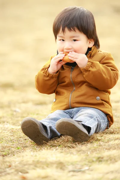 かわいい男の子の肖像画屋外でドーナツを食べる — ストック写真