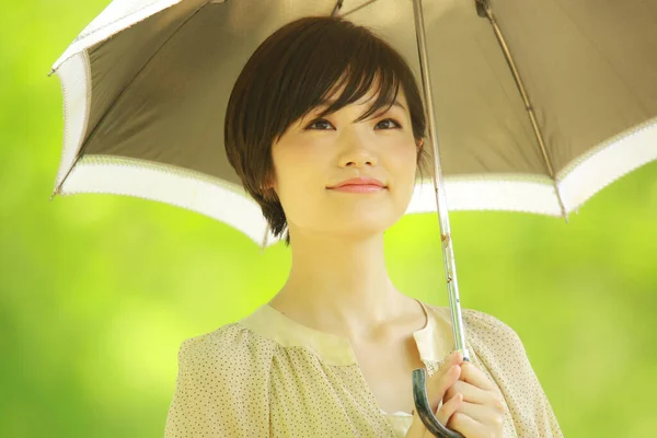 在公园里拿着雨伞的年轻亚洲女人的肖像 — 图库照片
