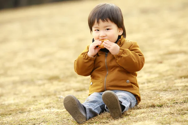 Netter Kleiner Junge Mit Donut Auf Dem Gras — Stockfoto