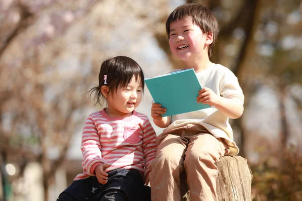 公園に座って本を読んでいる男の子と女の子 — ストック写真