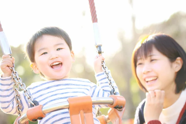 年轻的母亲和可爱的快乐的小儿子在公园的操场上玩耍 — 图库照片