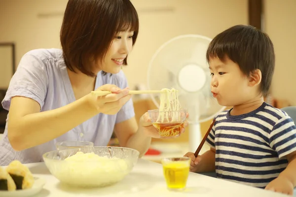 Asyalı anne ve oğlu evde yiyorlar.