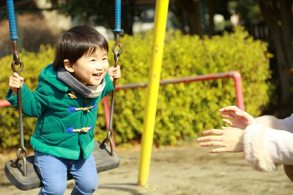 公園の遊び場で一緒に遊んでいる若い母親と愛らしい幸せな小さな息子 — ストック写真