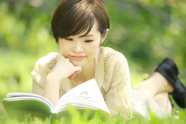 公園で本を読んでいる若いアジア人女性の肖像画 — ストック写真