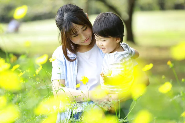 若いですアジアの女性とともに彼女の子供は公園で花を見て — ストック写真