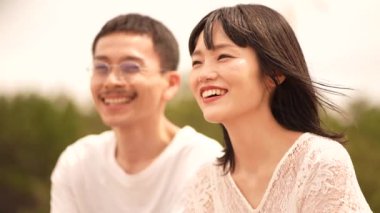 Deniz kıyısında poz veren beyaz elbiseli sevimli Japon çift.