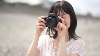 Gülümseyen Japon kadın dijital kamerayla fotoğraf çekiyor
