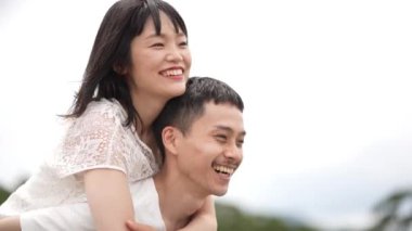 Deniz kıyısında poz veren beyaz elbiseli sevimli Japon çift.