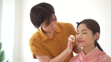 Makyaj sanatçısı kuaförde müşterinin yüzüne makyaj yapıyor. 