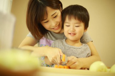 Anne ve oğul mutfakta birlikte yemek pişiriyorlar. 