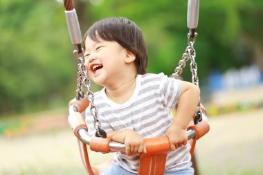 Asyalı küçük çocuk oyun alanında eğleniyor.