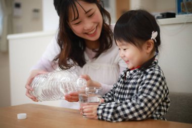 Anne ve kızı musluk suyu içiyor.