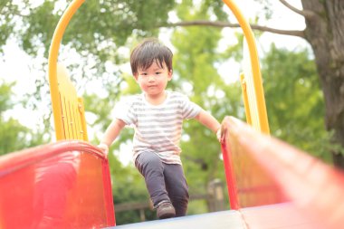 Asyalı küçük çocuk oyun alanında eğleniyor.