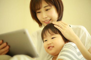 Mutlu anne ve oğul dijital tablette video izliyorlar.