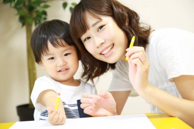 Anne ve oğul beyaz kağıda boya kalemleri çiziyor.