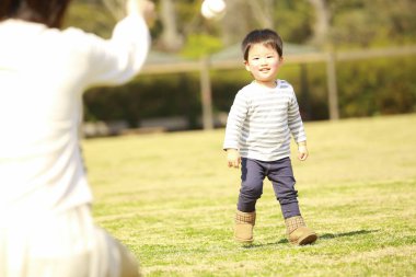 Genç anne ve sevimli küçük oğlu parkta birlikte oynuyorlar.