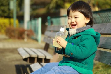 Küçük çocuk şişeden su içiyor.