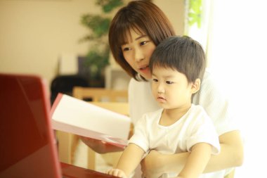 Asyalı genç kadın ve küçük oğlu dizüstü bilgisayar kullanıyor. 