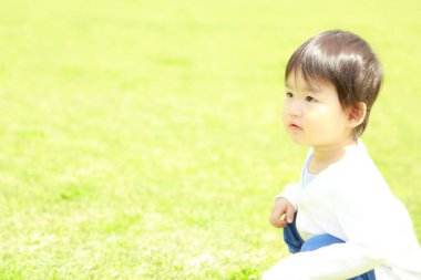 Parktaki çimenlikteki Asyalı küçük çocuk. 