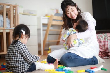 Genç Asyalı anne kızıyla ve küçük oğluyla oynuyor.