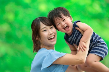 Genç Asyalı anne ve küçük oğlu parkta eğleniyorlar.  