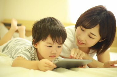 Mutlu anne ve oğul dijital tablette video izliyorlar.
