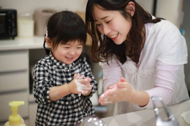 Anne kızına el yıkamayı öğretiyor.