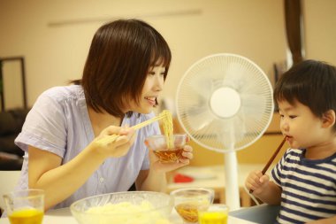 Asyalı anne ve oğlu evde yiyorlar.