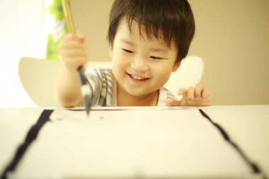 Küçük Japon çocuk fırça kaligrafi ile pratik yapıyor.