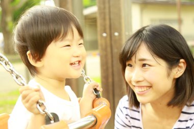 Genç Asyalı anne ve çocuğu oyun parkında.