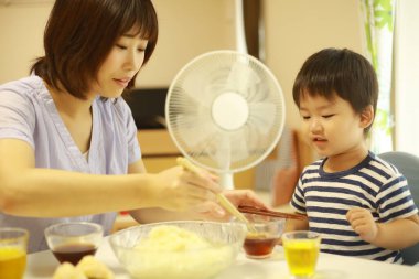 Asyalı anne ve oğlu evde yiyorlar.