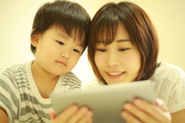 Mutlu anne ve oğul dijital tablette video izliyorlar.