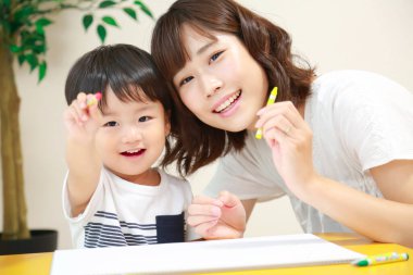 Anne ve oğul beyaz kağıda boya kalemleri çiziyor.