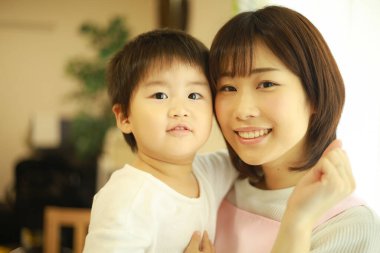 Asyalı genç kadın ve küçük oğlu poz veriyor.