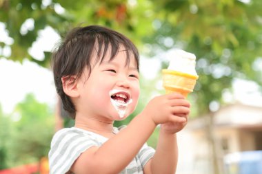 Parkta dondurma yiyen Asyalı küçük çocuk. 