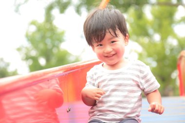 Asyalı küçük çocuk oyun alanında eğleniyor.