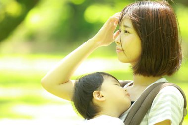 Genç Asyalı anne ve çocuğu parkta uyuyor.  