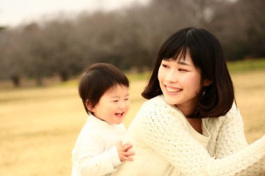 Genç Asyalı anne oğluyla parkta eğleniyor.  