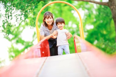 Genç Asyalı anne ve küçük oğlu oyun bahçesinde.