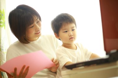 Asyalı genç kadın ve küçük oğlu dizüstü bilgisayar kullanıyor. 