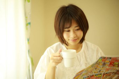 Gazete okuyan Asyalı genç bir kadının portresi