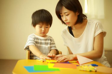 Genç Asyalı anne küçük oğluyla oynuyor.