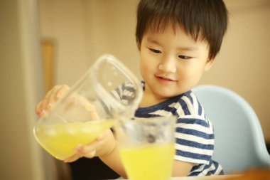 Bir bardak meyve suyu ile küçük tatlı Asyalı çocuk.