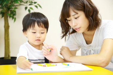 Anne ve oğul beyaz kağıda boya kalemleri çiziyor.